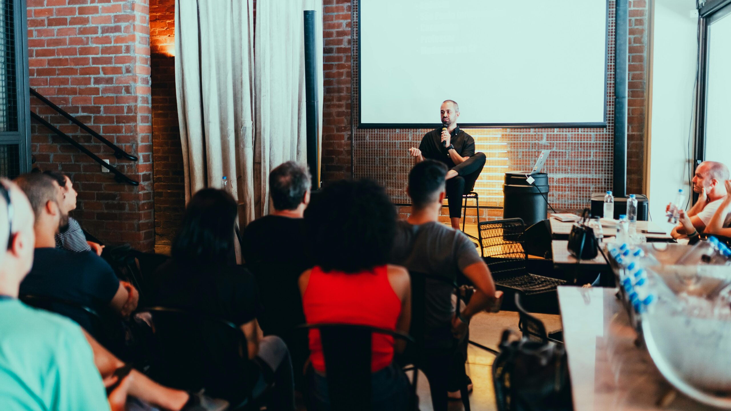 A dynamic seminar with a speaker engaging a diverse audience in a modern indoor setting.